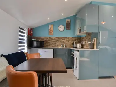 a kitchen with blue cabinets and a table with chairs at John Collingwood Bruce Suite - Uk43558 in Bowness-on-Solway
