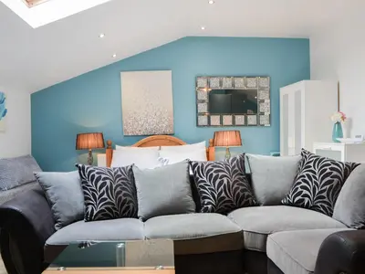 a living room with a couch and a blue wall at John Collingwood Bruce Suite - Uk43558 in Bowness-on-Solway
