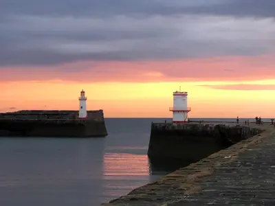 two lighthouses on a pier in the water at sunset at Coast To Coast Cottage in Cleator Moor