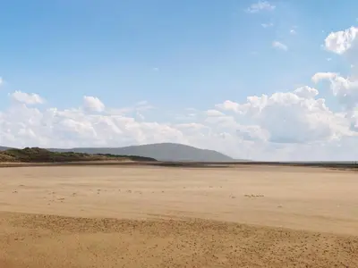 an empty beach with mountains in the background at Coast To Coast Cottage in Cleator Moor