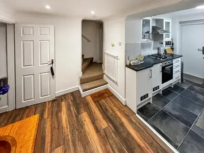 a kitchen with wooden floors and a white door at Coast To Coast Cottage in Cleator Moor
