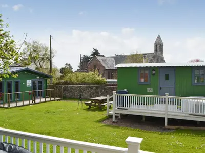 a green house with a bench in a yard at Jamie's Shepherds Hut - Uk43566 in Bowness-on-Solway