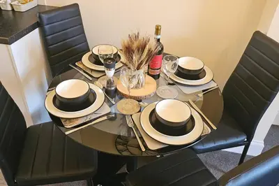 a table with hats and glasses and a bottle of wine at Quay cottage Annan in Annan