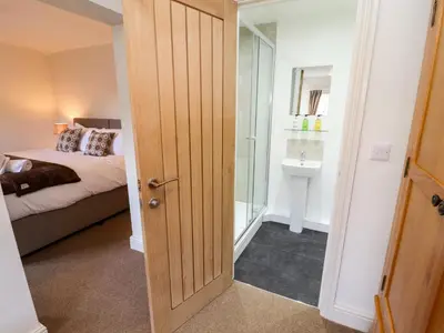 a bedroom with a bed and a door leading to a bathroom at Holborn Cottage, Blencathra Street in Keswick