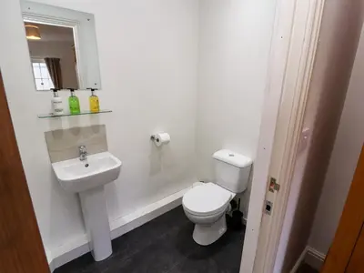 a white bathroom with a toilet and a sink at Holborn Cottage, Blencathra Street in Keswick