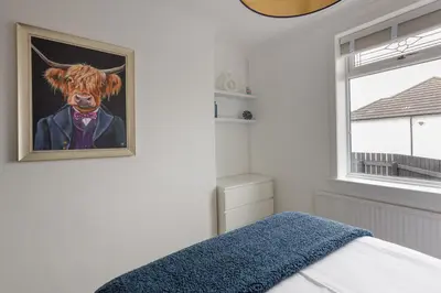 a bedroom with a painting of a cow on the wall at The Paddock at Brickrow Farm in Ayr