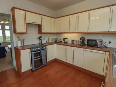a kitchen with wooden floors and white cabinets at Burnbank in Maryport