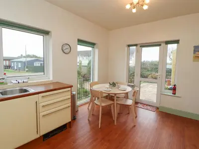 a kitchen with a table and chairs and windows at Burnbank in Maryport