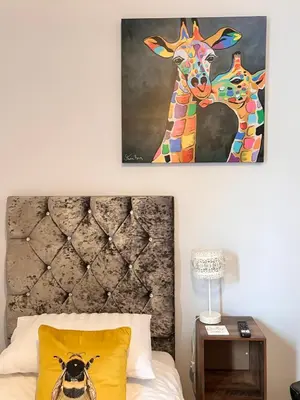 a painting of a giraffe on a wall above a bed at Cartref Guest House in Carlisle