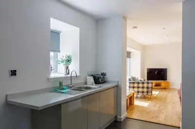 a kitchen with a sink and a living room at The Stables at Brickrow Farm in Ayr