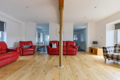 a living room with red furniture and wooden floors at The Stables at Brickrow Farm in Ayr