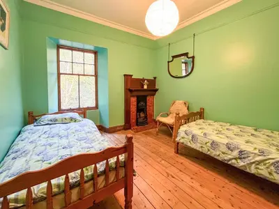 a green bedroom with two beds and a fireplace at Kirkdale in Kirkton