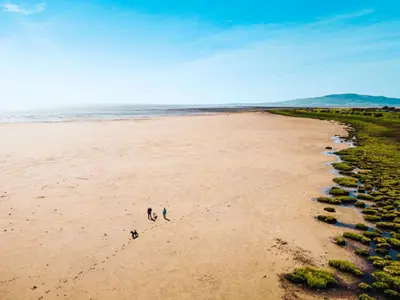 two people walking on a beach near the ocean at Queensberry Bay Essential Clover Caravan Pet in Annan