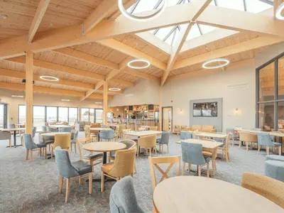 a dining room with tables and chairs and windows at Queensberry Bay Essential Clover Caravan Pet in Annan