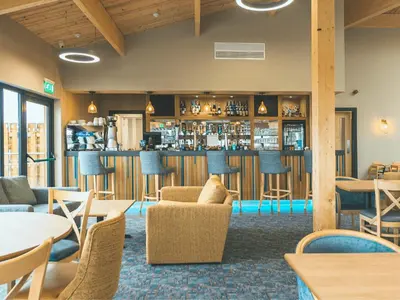 a restaurant with a bar with chairs and tables at Queensberry Bay Essential Clover Caravan in Annan
