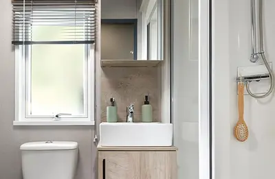 a bathroom with a sink and a toilet and a window at Queensberry Bay Essential Clover Caravan in Annan
