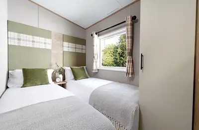 two beds in a small room with a window at Queensberry Bay Essential Clover Caravan in Annan
