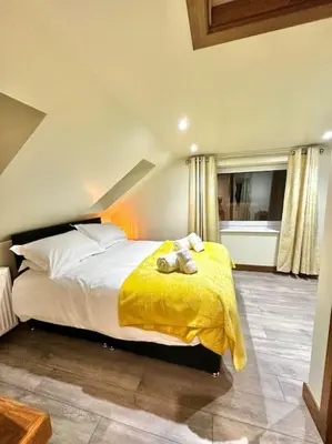 a bedroom with a large bed with a yellow blanket at The Anne'x in Dalbeattie
