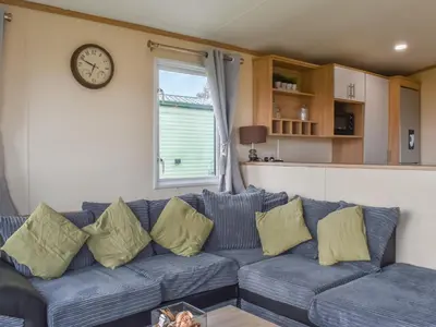 a blue couch in a living room with a clock on the wall at Regal Lodge in Plumbland