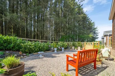 a wooden bench sitting in the middle of a garden at Antler Lodge - Meadows Retreat Lodge Park in Plumbland