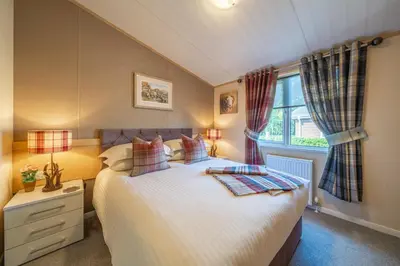 a bedroom with a large bed and a window at Antler Lodge - Meadows Retreat Lodge Park in Plumbland