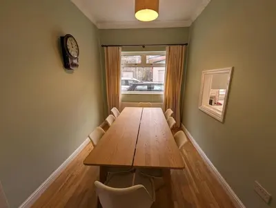 a dining room table with chairs and a clock on the wall at Luxurious Georgian Town House in Langholm