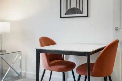 a table with two orange chairs and a white table at George St Getaway in Ayr