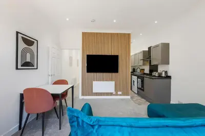 a living room with a table and a tv in a kitchen at George St Getaway in Ayr