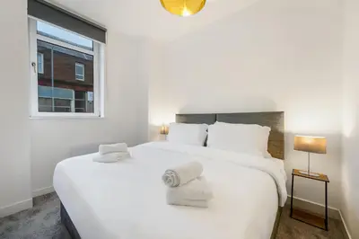 a white bedroom with a large white bed and a window at George St Getaway in Ayr