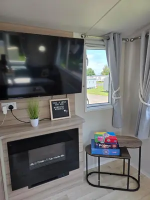 a living room with a tv and a fireplace at Barbara's Caravan Craig Tara in Ayr