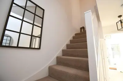 a mirror on the wall next to a staircase at Lake District Haven - Modern Comfort in Cockermouth in Cockermouth