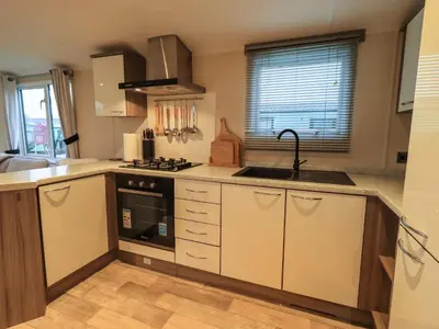 a kitchen with a sink and a stove top oven at Highlands Way Lodge in Workington
