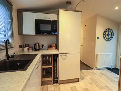 a small kitchen with a refrigerator and a sink at Highlands Way Lodge in Workington