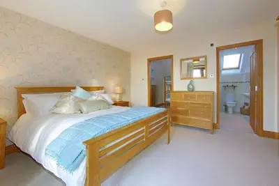 a bedroom with a large bed and a bathroom at Inchlonaig House in Port William