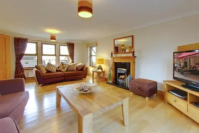 a living room with a couch and a table and a tv at Inchlonaig House in Port William