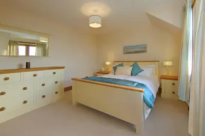 a bedroom with a bed with a dresser and a mirror at Inchlonaig House in Port William