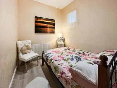 a small bedroom with a bed and a chair at Beachcomber Apartment in Girvan