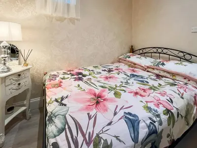 a bedroom with a bed with a floral bedspread at Beachcomber Apartment in Girvan