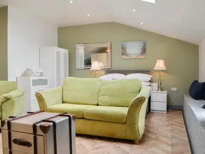 a living room with a yellow couch and a bed at Tiberius Claudius Augustus Suite - Uk43559 in Bowness-on-Solway