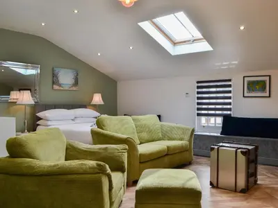 a bedroom with a bed and chairs and a skylight at Tiberius Claudius Augustus Suite - Uk43559 in Bowness-on-Solway