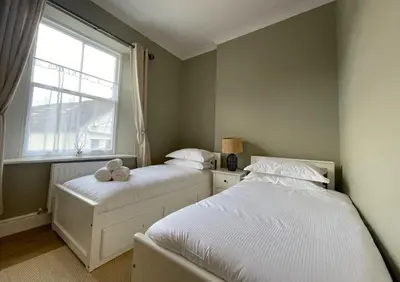 two beds in a small bedroom with a window at The Tops in Keswick