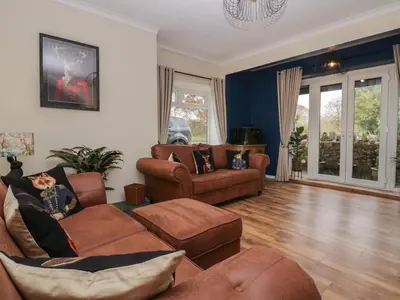 a living room with brown furniture and blue walls at Benstead Cottage in Seascale