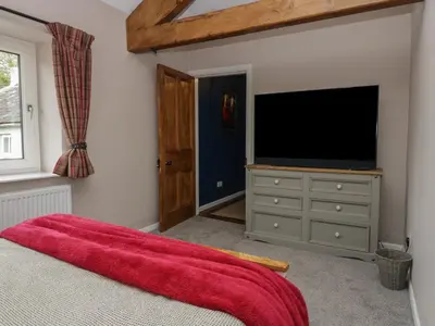 a bedroom with a flat screen tv and a bed at Benstead Cottage in Seascale