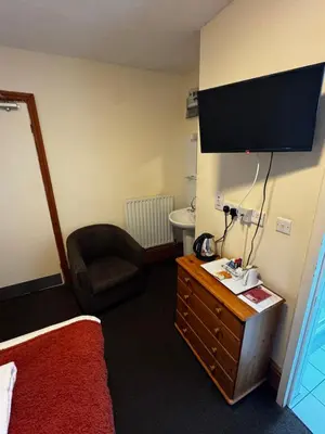 a hotel room with a bed and a television on the wall at The Wasdale Head Inn & Apartments in Seascale