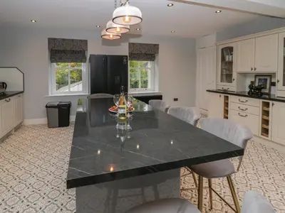 a kitchen with a large black table and chairs at Beechgrove Manor in Workington