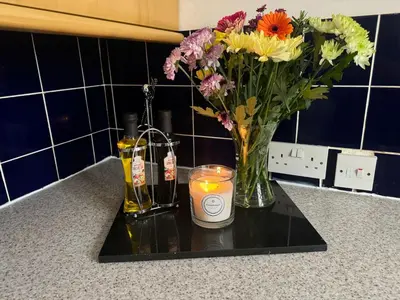 a candle and a vase with flowers on a counter at Robinson's Retreat - Cockermouth - Lake District in Cockermouth