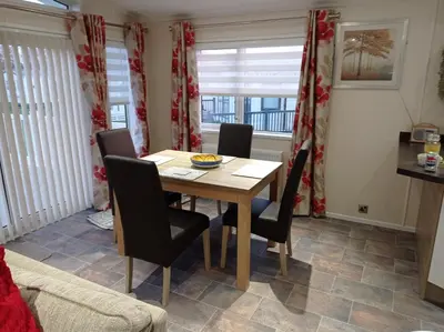 a dining room with a wooden table and chairs at Muirfield cosy retreat in Girvan