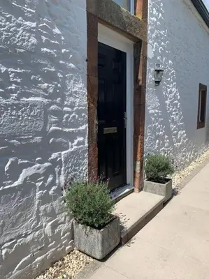 a black door on a building with two potted plants at Watchhall, Annan, Dumfries & Galloway, Scotland Barn - 2 Bed in Annan