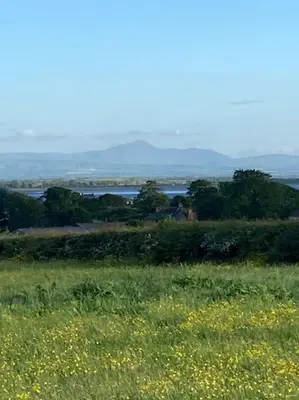a field of grass and flowers with a body of water at Watchhall, Annan, Dumfries & Galloway, Scotland Barn - 2 Bed in Annan