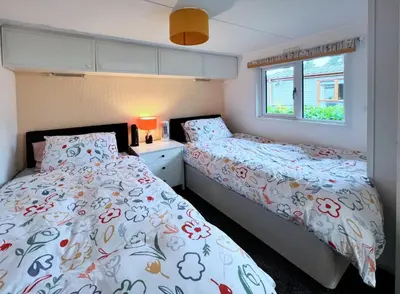 a bedroom with two beds and a window at Lodge by the Lake - Lake District - Hot Tub in Bassenthwaite